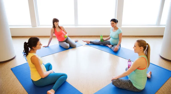 Glada gravida kvinnor sitter på mattor i gym — Stockfoto