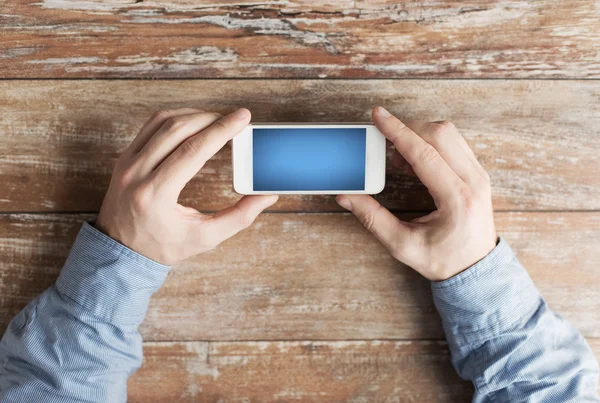 Close up of male hands with smartphone on table — Stock Photo, Image