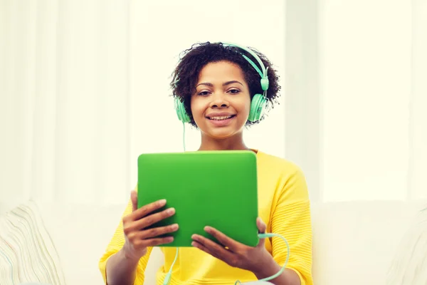 Mujer africana feliz con la PC tableta y auriculares —  Fotos de Stock
