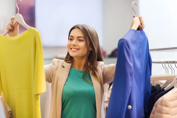 Gelukkig jonge vrouw kleding in winkelcentrum kiezen — Stockfoto