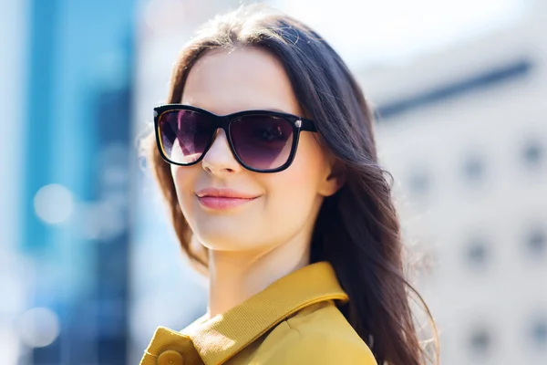 Giovane donna sorridente con occhiali da sole in città — Foto Stock