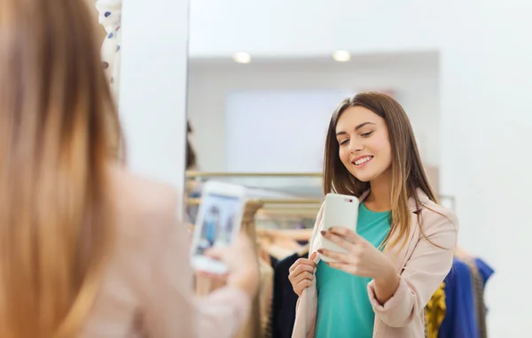 Женщина делает зеркальное селфи на смартфоне в магазине — стоковое фото