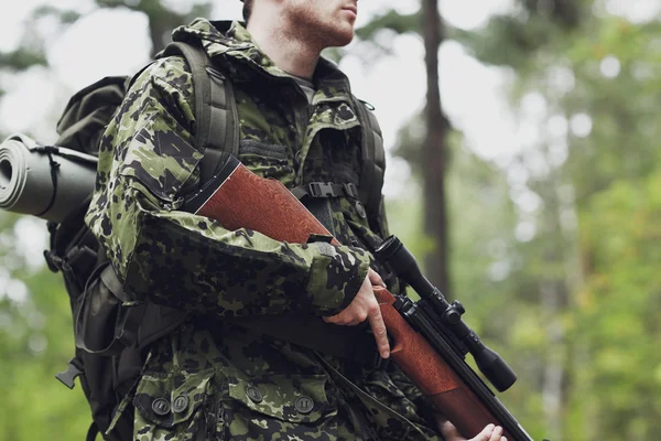 Close up of soldier or hunter with gun in forest — Stock Photo, Image