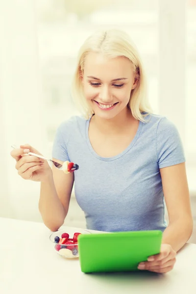 微笑的女人在家里吃水果与平板电脑 — 图库照片