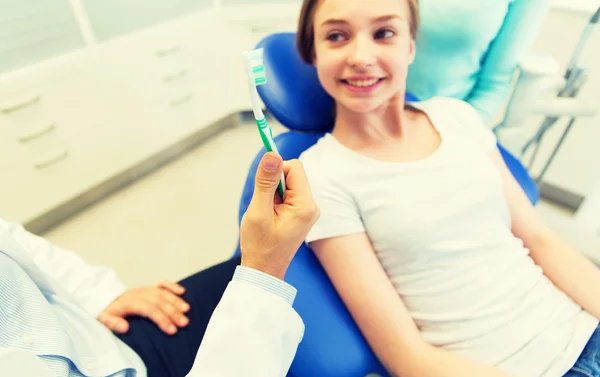 Primer plano de la mano del dentista con cepillo de dientes y niña — Foto de Stock