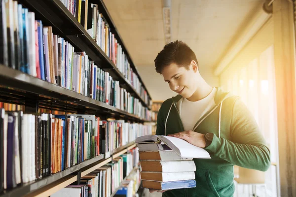 Счастливый студент или человек с книгой в библиотеке — стоковое фото