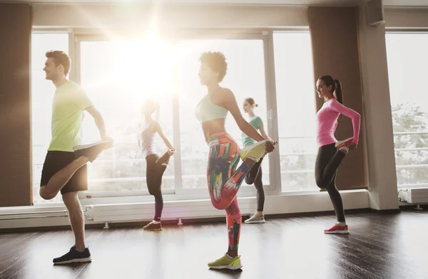 Grupo de personas sonrientes haciendo ejercicio en el gimnasio —  Fotos de Stock