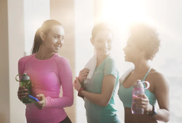 Gelukkig vrouwen met flessen water in de sportschool — Stockfoto
