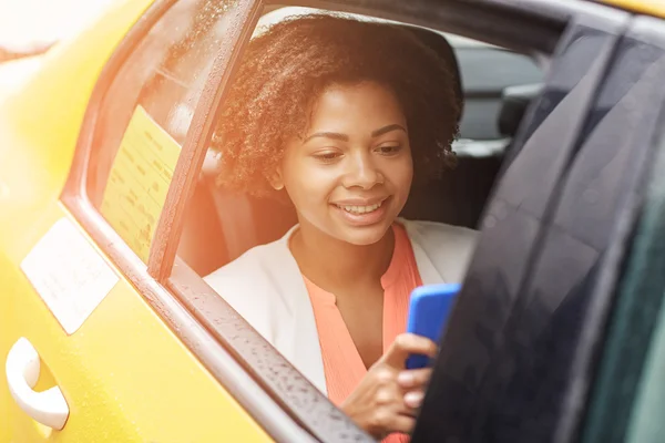 Glückliche Afrikanerin tickt im Taxi auf Smartphone — Stockfoto