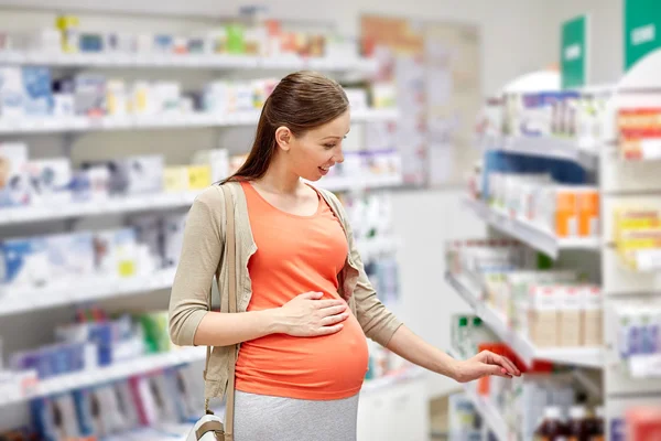 Gelukkig zwangere vrouw kiezen geneeskunde bij apotheek — Stockfoto