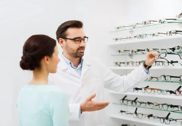 Mujer y óptico mostrando gafas en la tienda de óptica — Foto de Stock