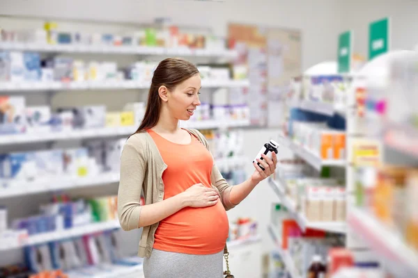 Gelukkig zwangere vrouw met medicatie bij apotheek — Stockfoto