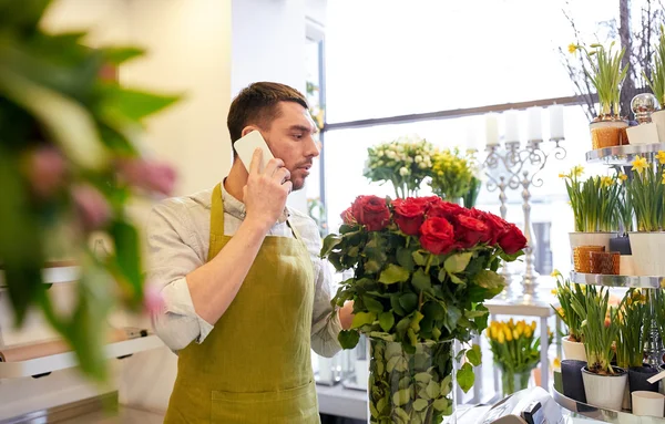 Hombre con smartphone y rosas rojas en floristería — Foto de Stock
