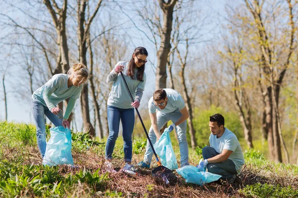 Voluntários com sacos de lixo área do parque de limpeza — Fotografia de Stock