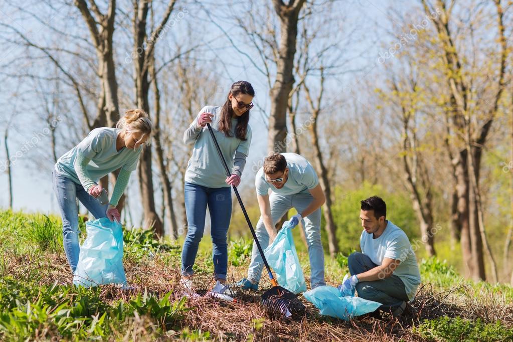 Volunteers with garbage bags cleaning park area Stock Photo by ©Syda