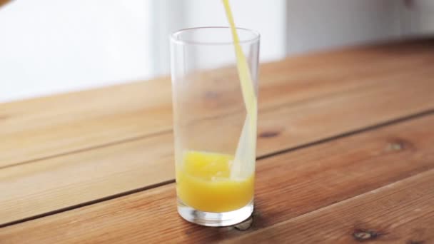 Zumo de naranja vertiendo en el vaso en la mesa de madera — Vídeos de Stock