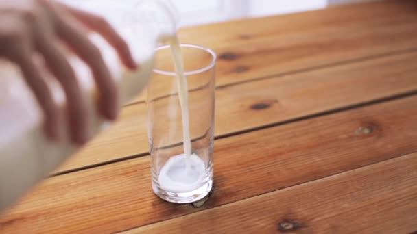 Hand gieten melk in lege glas op houten tafel — Stockvideo