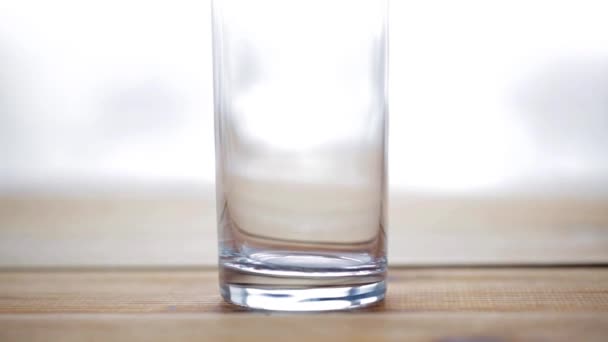 Agua vierte en vidrio sobre mesa de madera — Vídeos de Stock