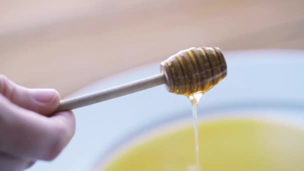 Рука держа ковша с медом льется на тарелку — стоковое видео