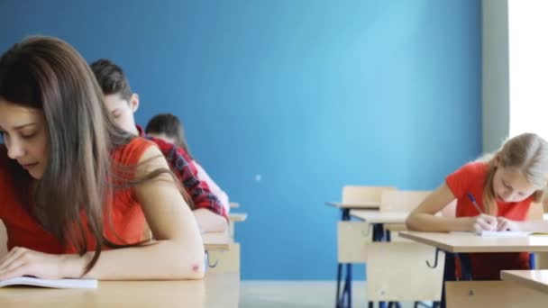 Estudiantes con cuadernos prueba de escritura en la escuela — Vídeo de stock