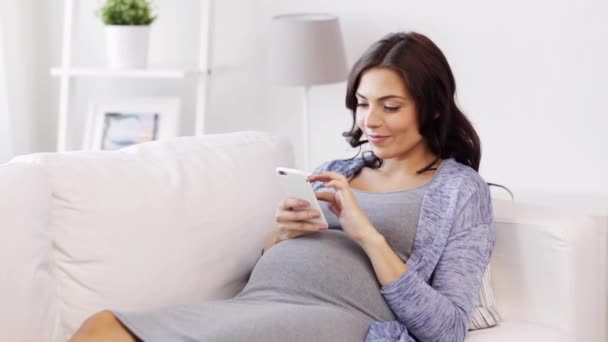 Glad gravid kvinna med smartphone hemma — Stockvideo