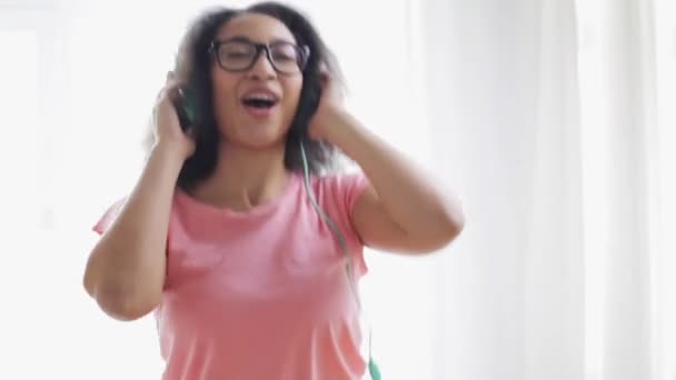 Mujer africana feliz en auriculares bailando en casa — Vídeos de Stock