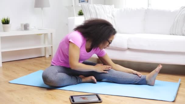 Mujer africana con tableta pc haciendo ejercicio en casa — Vídeos de Stock
