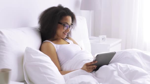 African woman with tablet pc in bed at home — Stock Video