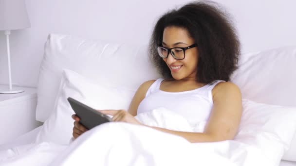 African woman with tablet pc in bed at home — Stock Video