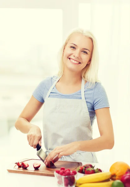 Sonriente joven mujer cortando frutas en casa — Foto de Stock