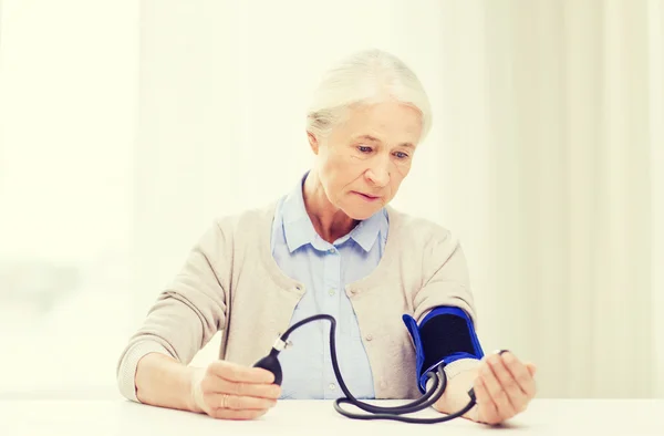 Mulher idosa com tonômetro verificando a pressão arterial — Fotografia de Stock