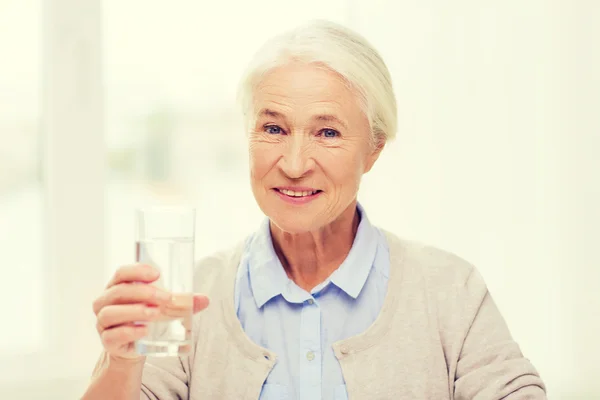 Felice donna anziana con un bicchiere d'acqua a casa — Foto Stock
