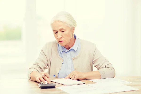 Seniorin mit Papieren und Taschenrechner zu Hause — Stockfoto