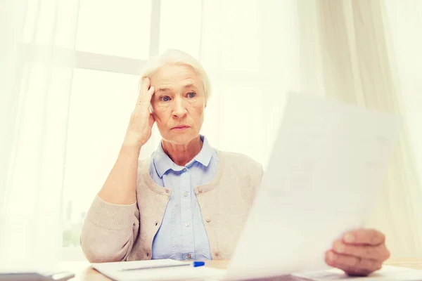 Seniorin mit Papieren und Taschenrechner zu Hause — Stockfoto