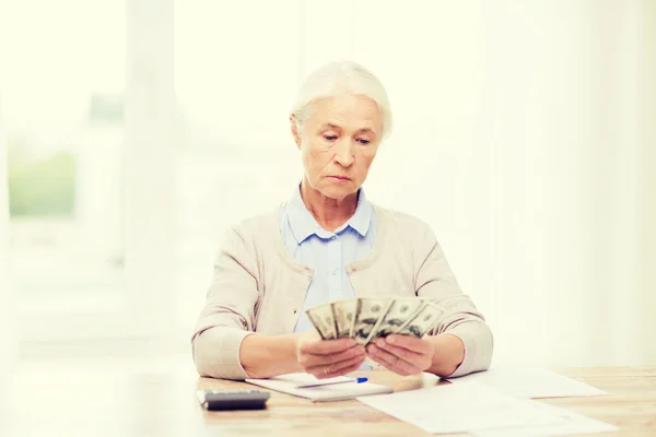 Senior femme avec de l'argent et des papiers à la maison — Photo