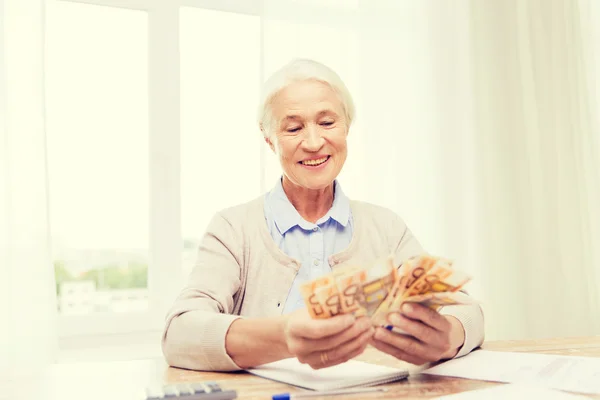 Seniorin mit Geld und Papieren zu Hause — Stockfoto