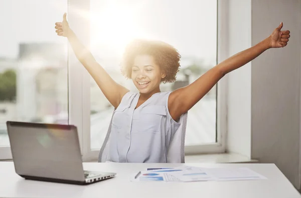 Mujer africana feliz con el ordenador portátil en la oficina — Foto de Stock