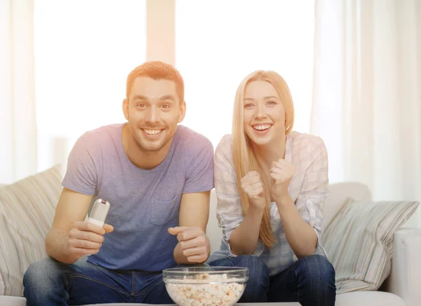 Lächelndes Paar mit Popcorn jubelndem Sportteam — Stockfoto