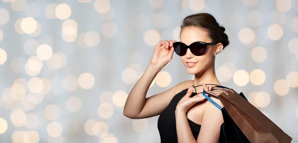 Femme heureuse en lunettes de soleil noires avec des sacs à provisions — Photo