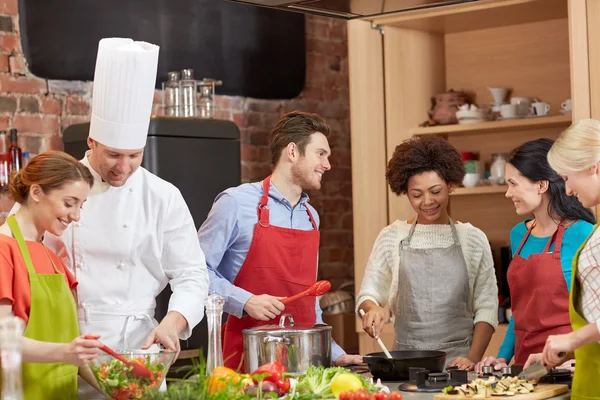 Happy friends en chef kok koken in de keuken — Stockfoto