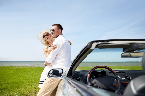 Feliz casal abraçando perto de carro cabriolet no mar — Fotografia de Stock