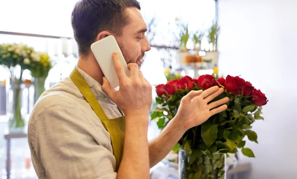 Homem com smartphone e rosas vermelhas na loja de flores — Fotografia de Stock