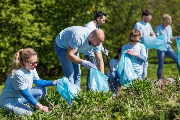 Voluntários com sacos de lixo área do parque de limpeza — Fotografia de Stock