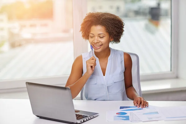 Mujer africana feliz con el ordenador portátil en la oficina — Foto de Stock