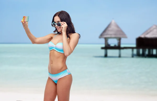 Woman in bikini taking smatphone selfie on beach — Zdjęcie stockowe