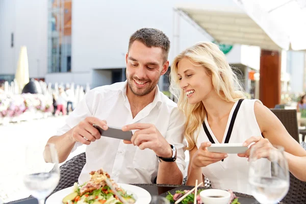 Feliz pareja con smatphone fotografiando comida — Foto de Stock