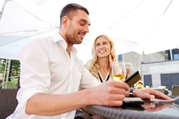 Feliz pareja con billetera pagando la factura en el restaurante — Foto de Stock