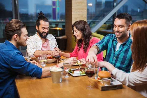 Amigos comer e degustação de alimentos no restaurante — Fotografia de Stock