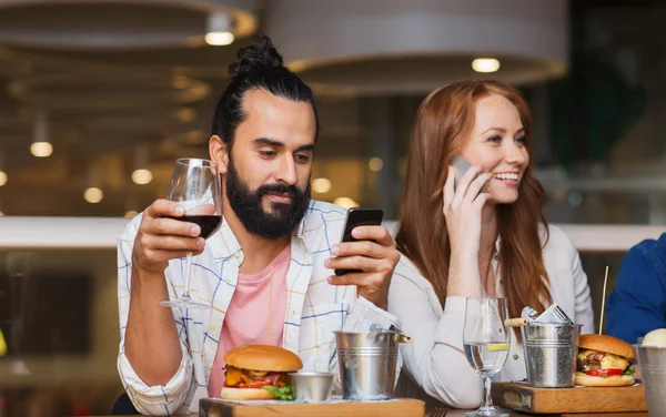 Mutlu arkadaş smartphones vasıl restoran grubu — Stok fotoğraf