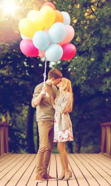 Couple with colorful balloons kissing in the park — Stock Photo, Image